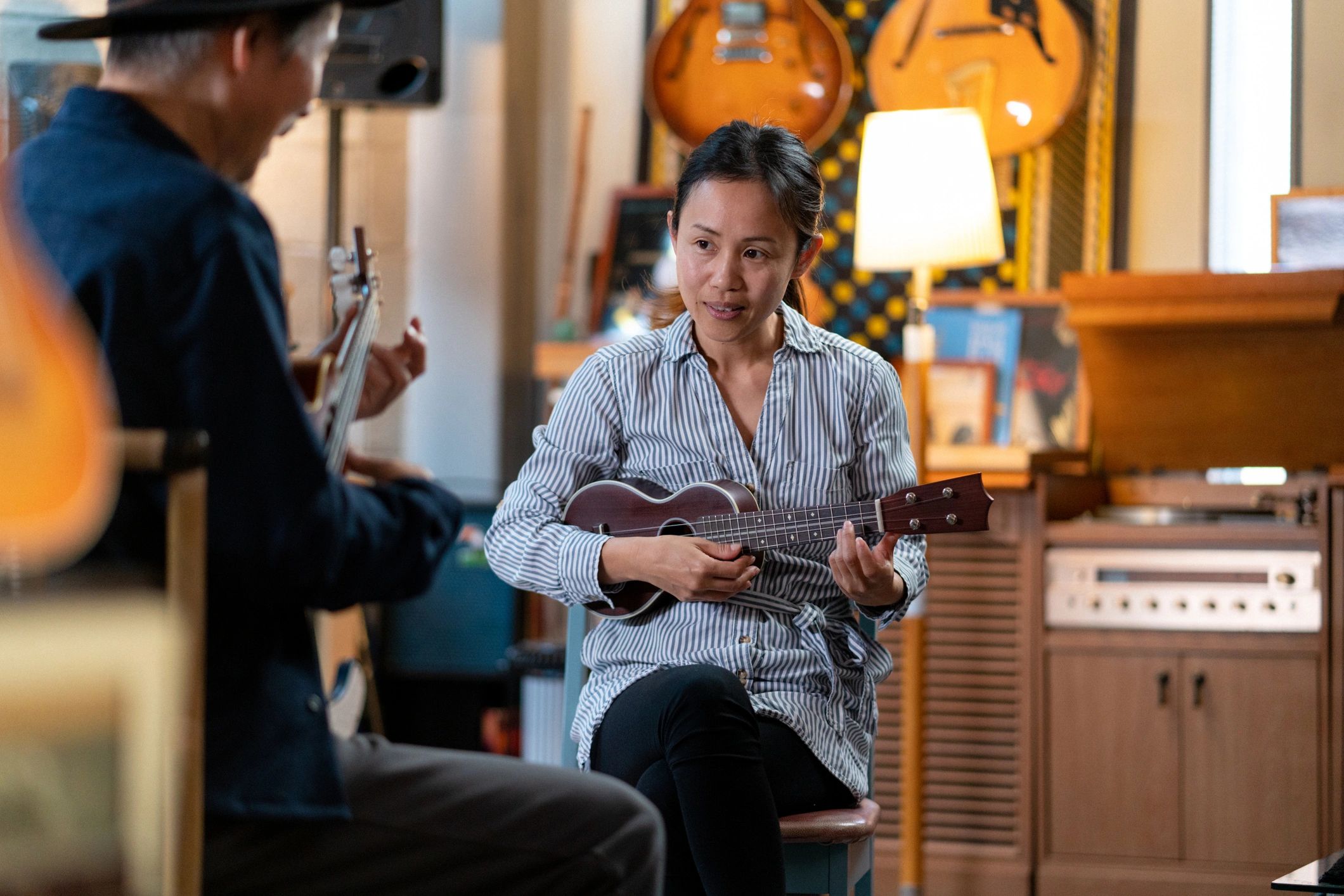 Adult student learning guitar-style string instrument