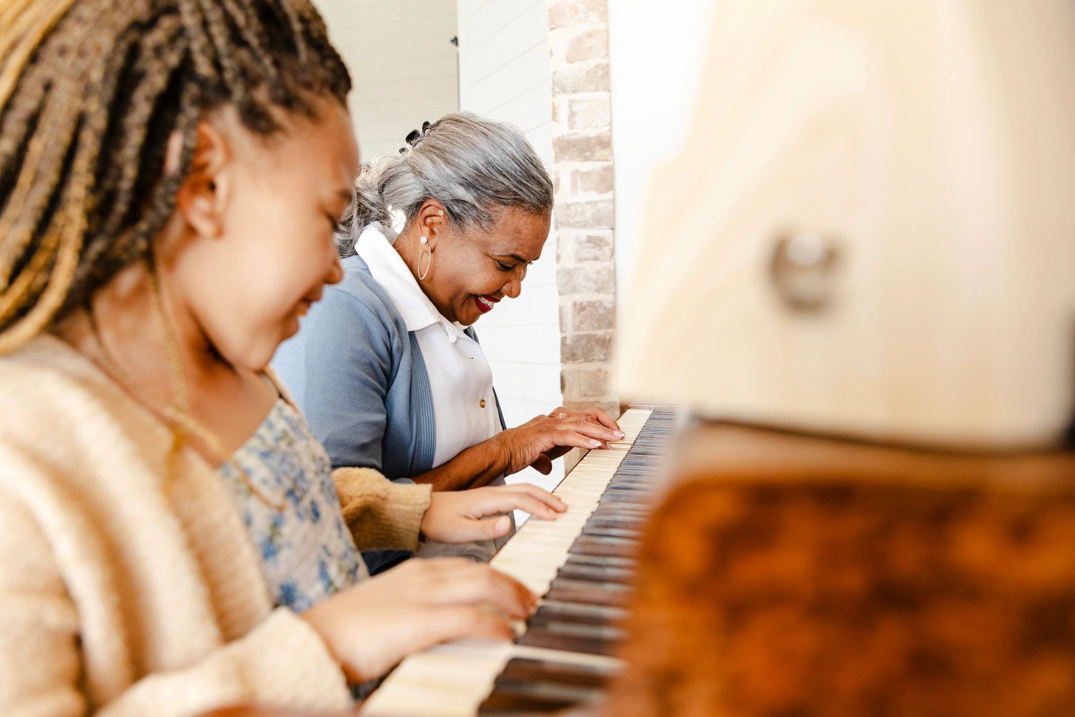 Student practicing piano with a supportive teacher