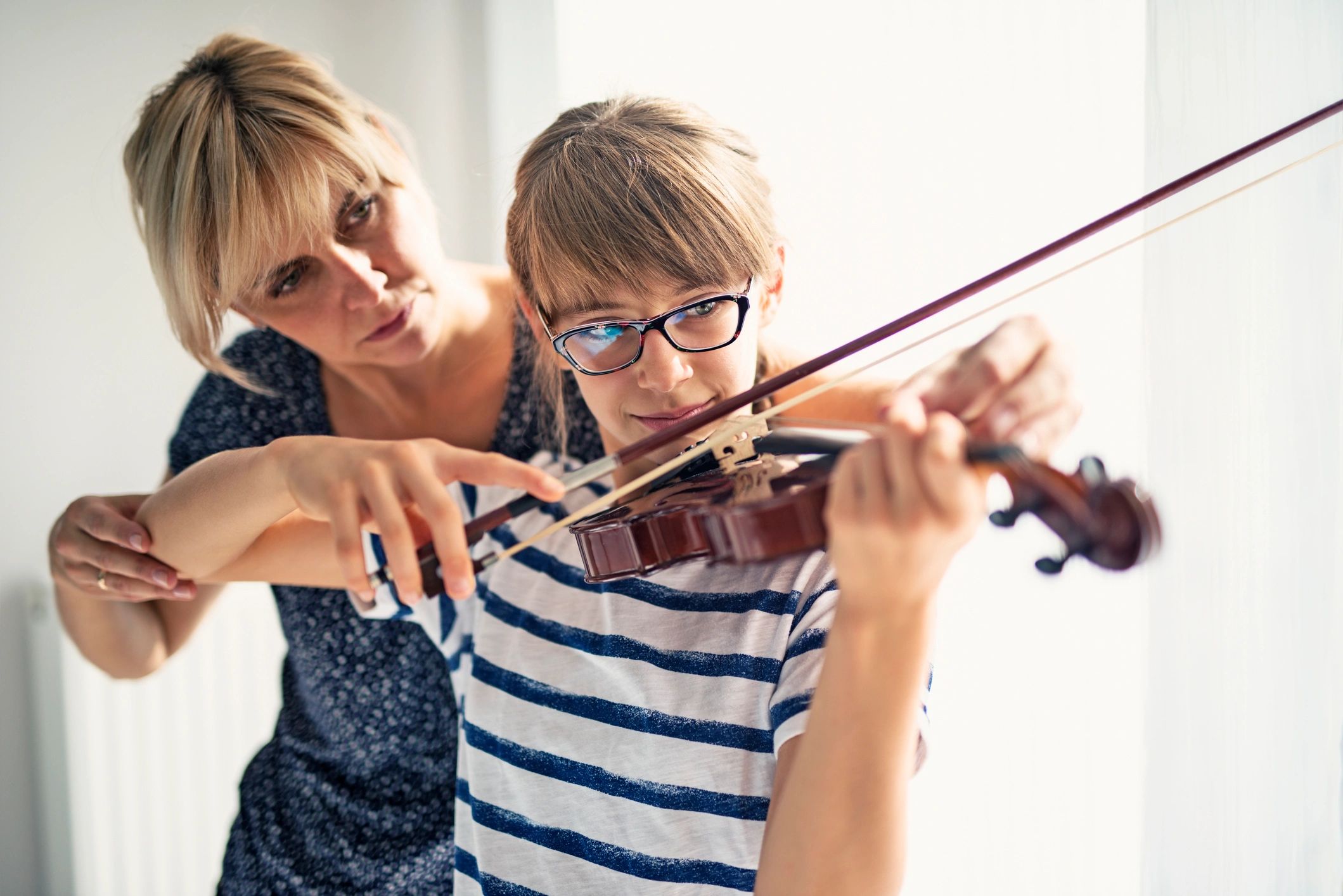 Young student practicing violin with guidance